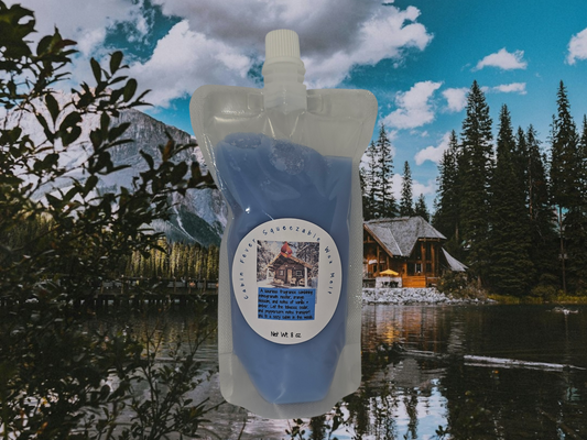 A squeezable wax melt packet with a mountain and cabin in the background.